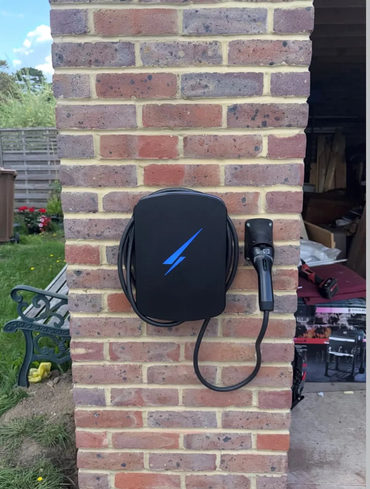 Wall-mounted home EV charger with tethered cable on a brick pillar in Reigate